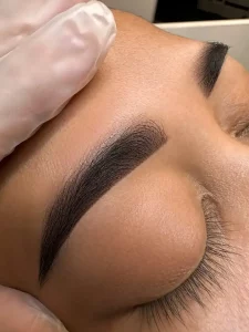 Client receiving permanent brow tattoo treatment at getBeauty in Cambridge for long-lasting, natural eyebrows
